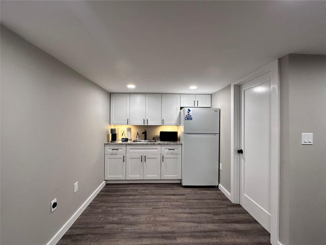 Kitchen featuring freestanding refrigerator, dark wood finished floors, white cabinets, recessed lighting, and light stone countertops | Image 16