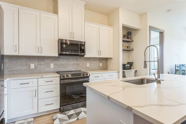 Kitchen featuring appliances with stainless steel finishes, white cabinets, tasteful backsplash, and light stone counters | Image 12