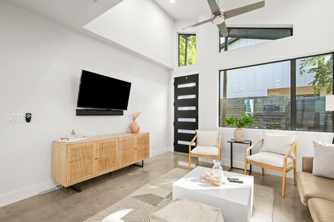 Living room with concrete floors, a ceiling fan, recessed lighting, and a high ceiling | Image 10