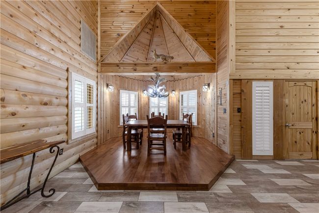 Dining space with a chandelier, a high ceiling, and wood walls | Image 10