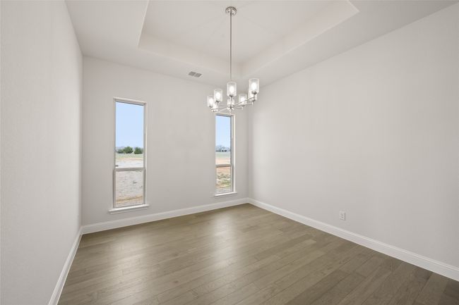 Spare room featuring a chandelier, a raised ceiling, dark wood-type flooring, and baseboards | Image 14