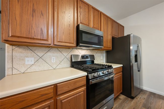 Kitchen featuring stainless steel appliances, light wood-style floors, brown cabinets, and decorative backsplash | Image 22