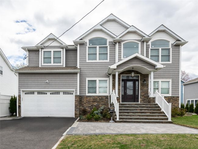 View of front of property featuring an attached garage, stone siding, and driveway | Image 27