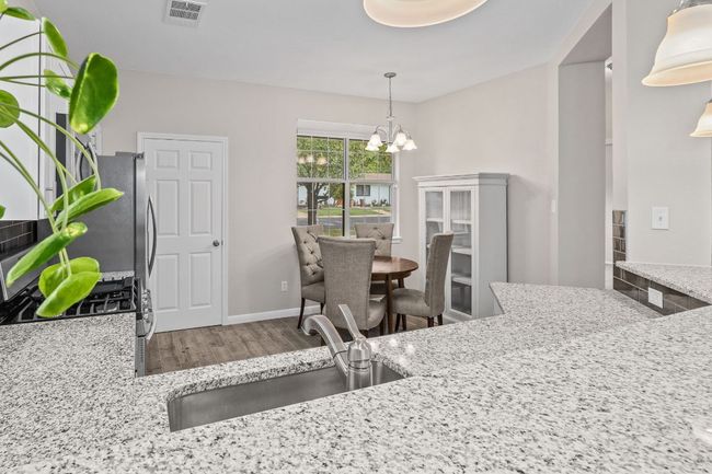 Kitchen featuring wood finished floors, an inviting chandelier, a sink, visible vents, and pendant lighting | Image 21