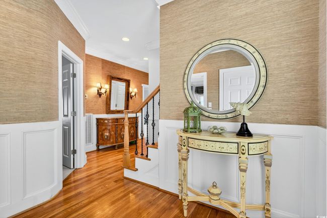 Corridor featuring ornamental molding, a wainscoted wall, wood finished floors, a decorative wall, and stairs | Image 22