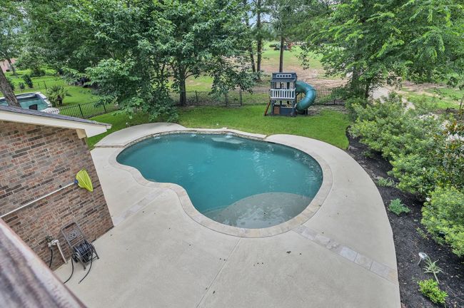 View from the balcony overlooking the backyard pool and lush golf course beyond. | Image 38