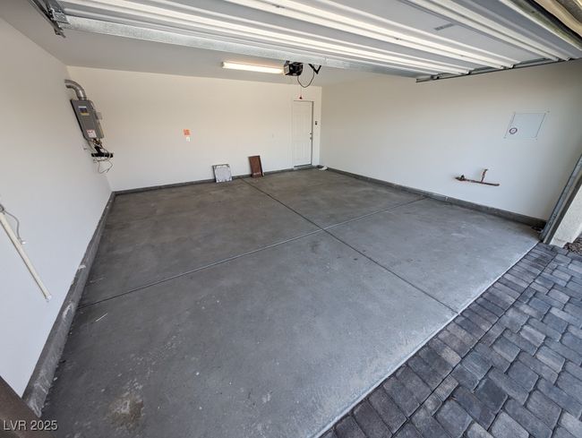 Garage featuring strapped water heater and a garage door opener | Image 38