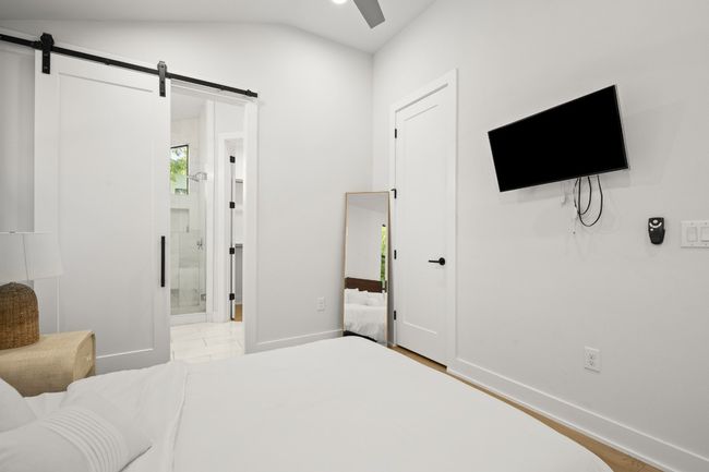 Bedroom featuring a barn door, ensuite bathroom, vaulted ceiling, and ceiling fan | Image 20