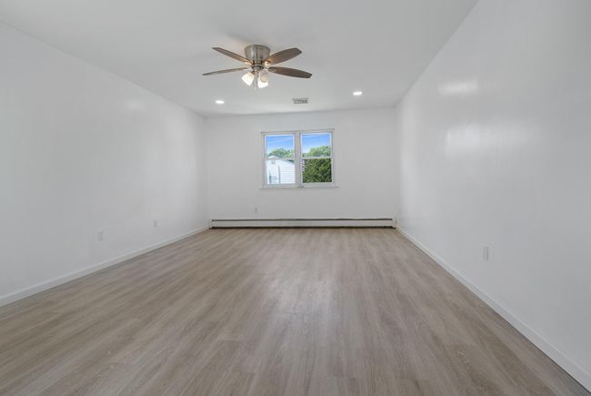 Spare room with a baseboard radiator, a ceiling fan, light wood finished floors, and baseboards | Image 24