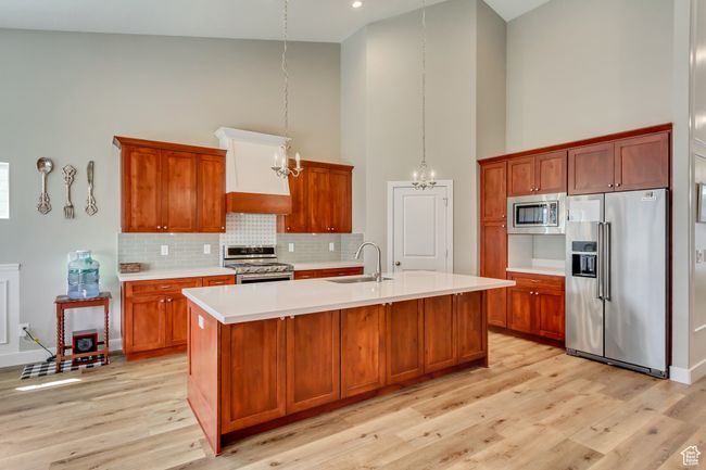 Kitchen featuring stainless steel appliances, a sink, a notable chandelier, light countertops, and high vaulted ceiling | Image 9