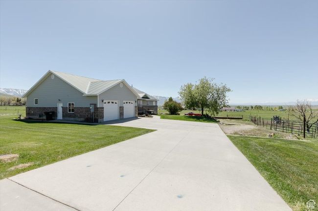 View of side of property featuring driveway, brick siding, an attached garage, and a mountain view | Image 12