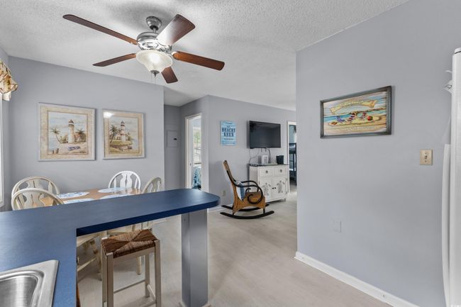Dining room featuring a ceiling fan, light wood-style flooring, a textured ceiling, and baseboards | Image 13