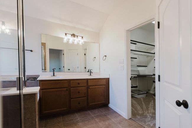 Full bathroom with tile patterned flooring, vaulted ceiling, double vanity, and a sink | Image 30