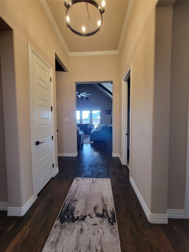 Hall with crown molding, a chandelier, and dark wood-type flooring | Image 9