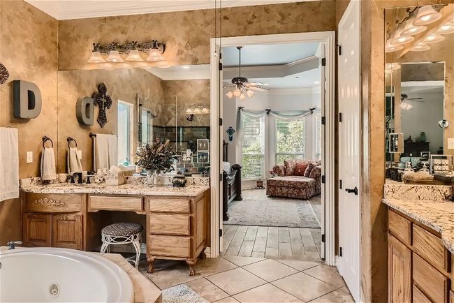 Ensuite bathroom featuring ensuite bathroom, a tub with jets, crown molding, ceiling fan, and vanity | Image 22