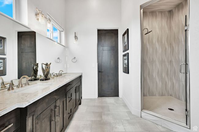 Bathroom featuring a shower stall, double vanity, baseboards, and tile patterned flooring | Image 32