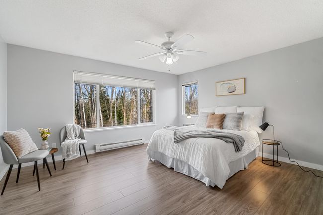 Bedroom with a textured ceiling, a baseboard radiator, wood finished floors, a ceiling fan, and baseboards | Image 20