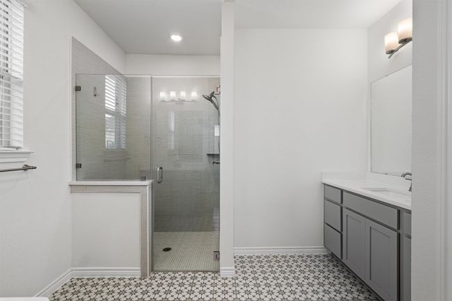 Primary full bath with dual vanities & sinks, a glass walk-in shower with seat. Trendy tile flooring adds a nice touch! | Image 13