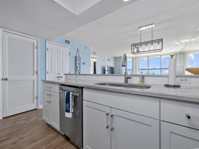 Kitchen featuring a sink, visible vents, stainless steel dishwasher, and a textured ceiling | Image 13