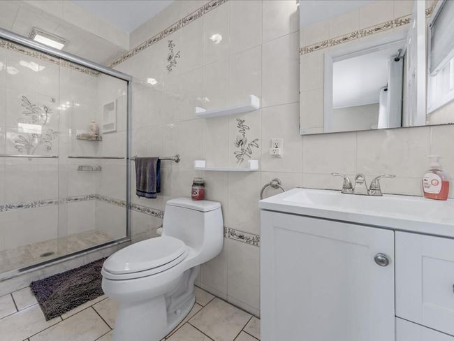 Bathroom with toilet, a stall shower, and tile walls | Image 17