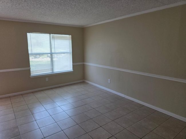 Empty room featuring a textured ceiling, tile patterned floors, and ornamental molding | Image 4