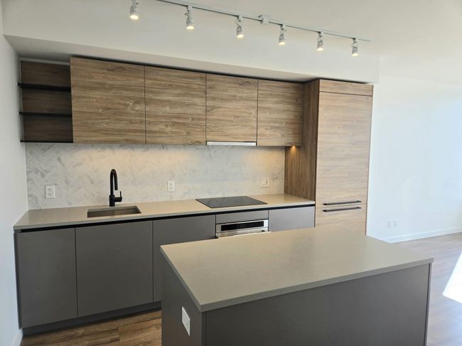 Kitchen featuring open shelves, modern cabinets, rail lighting, and a sink | Image 7