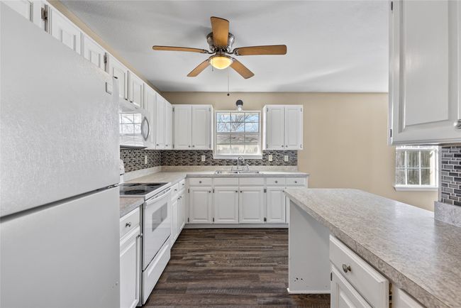 Kitchen with white appliances, light countertops, a sink, and decorative backsplash | Image 31