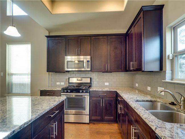 Modern kitchen with granite counter and stainless steel appliances. | Image 7