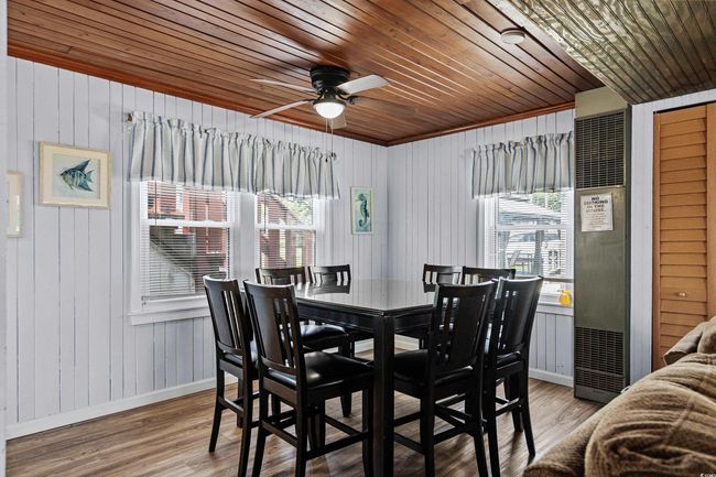 Dining space with baseboards, wood ceiling, wooden walls, wood finished floors, and a ceiling fan | Image 5