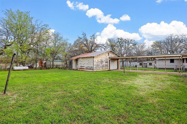 View of yard with a garage, driveway, an outdoor structure, and a carport | Image 4
