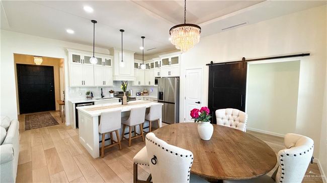 Dining space featuring a barn door, a chandelier, light wood finished floors, and recessed lighting | Image 12