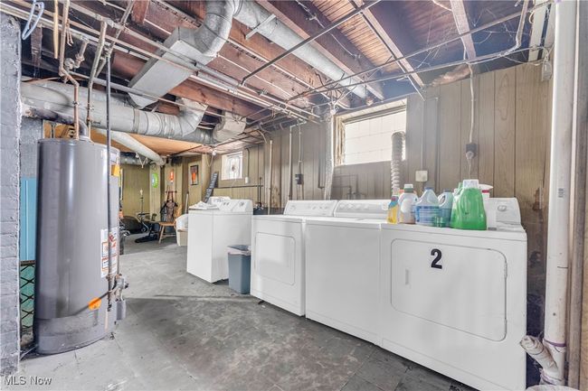 Below grade area featuring gas water heater, wood walls, and independent washer and dryer | Image 21