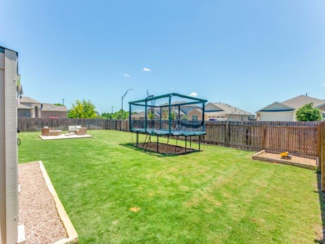 Fenced backyard with a trampoline, an outdoor living space, and a patio | Image 34
