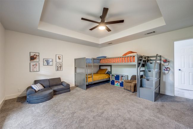 Carpeted bedroom with a tray ceiling, baseboards, and ceiling fan | Image 19