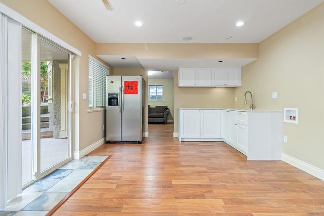 Kitchen with stainless steel fridge, light wood-style floors, white cabinetry, baseboards, and recessed lighting | Image 5