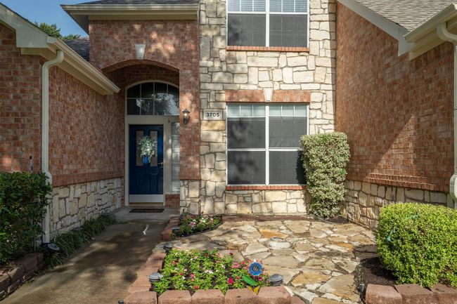 Property entrance featuring a shingled roof, brick siding, and stone siding | Image 4