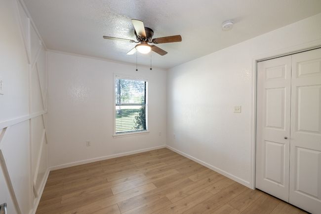 Spare room with light wood-style flooring, a textured ceiling, baseboards, and a ceiling fan | Image 19