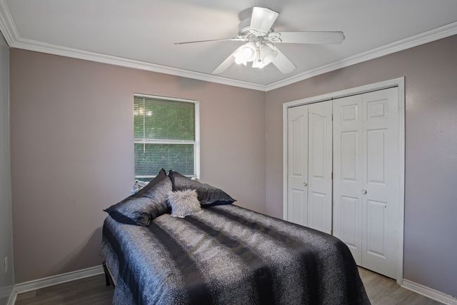 Bedroom with ornamental molding, light wood-style flooring, a closet, and ceiling fan | Image 17