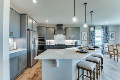 This Whitney floorplan home has a gourmet kitchen with 5-burner gas cooktop, quartz countertops, subway tile backsplash, wood hood, and stainless steel oven, microwave and dishwasher! | Image 2