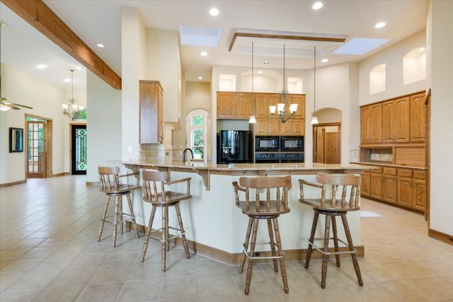 Yes, that is 2 ovens, 2 microwaves and 2 appliance garages! There are cabinets & drawers galore under the huge island. The walk-in pantry is ideal for your ingredients! Art niches w/ spot lights above the cabinets. Sky lights, recessed, spot, pendant, and indirect lighting for everything day and night! Strategically located between both dining areas and out of view of the living room. However, the view across the back is not lost! | Image 9