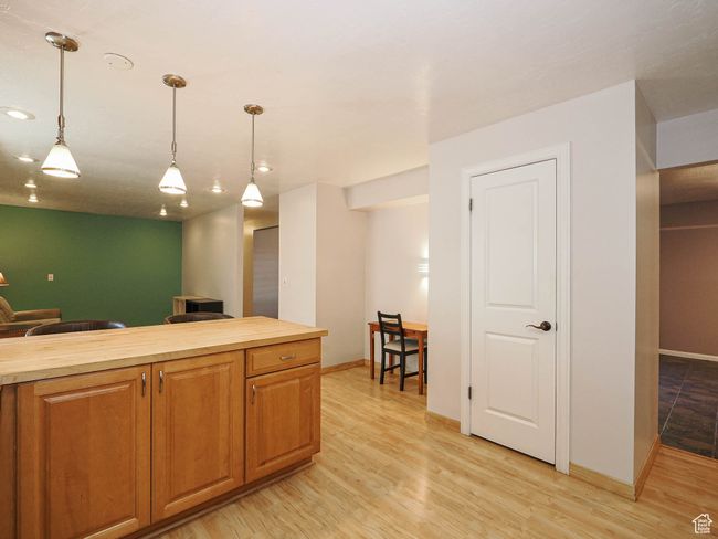 Kitchen featuring butcher block countertops, decorative light fixtures, light wood-style flooring, baseboards, and recessed lighting | Image 11