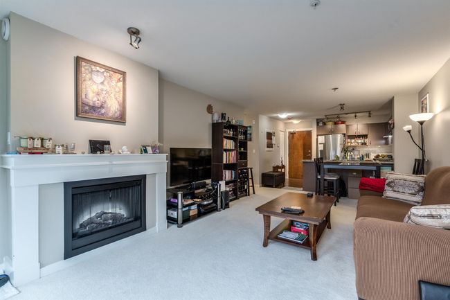 Living room with rail lighting, a fireplace, and carpet | Image 11