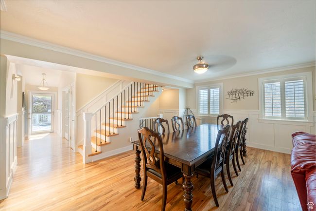 Dining area featuring light wood-style floors, ornamental molding, a wainscoted wall, and stairway | Image 18