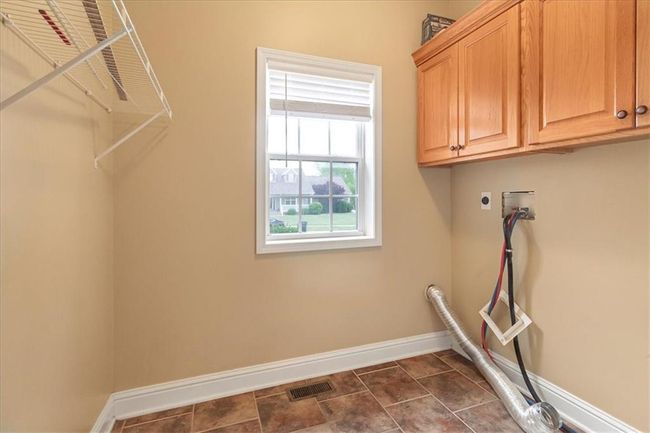 Clothes washing area with cabinet space, washer hookup, baseboards, hookup for an electric dryer, and visible vents | Image 26
