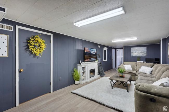 Living area featuring wood finished floors and a warm lit fireplace | Image 20