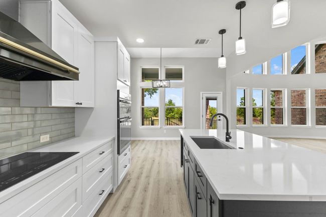 The kitchen has upgrades galore including recessed lighting, island with sink | Image 10