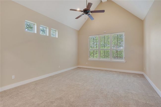 Empty room with plenty of natural light, light colored carpet, high vaulted ceiling, a ceiling fan, and baseboards | Image 22