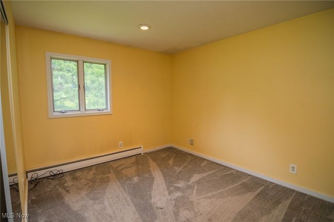 Empty room featuring dark carpet, a baseboard heating unit, baseboards, and recessed lighting | Image 22