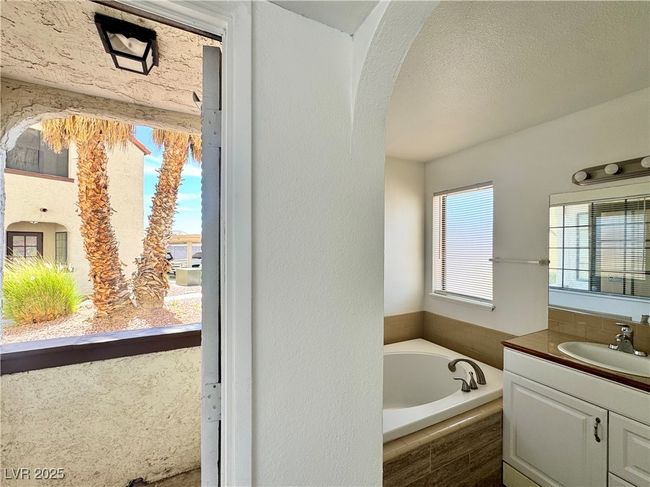 Primary Bed/Bathroom with vanity sink, tub, and a textured ceiling | Image 16
