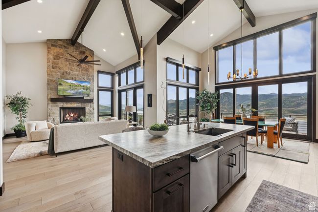 Kitchen featuring beamed ceiling, stainless steel dishwasher, high vaulted ceiling, a stone fireplace, and healthy amount of natural light | Image 18